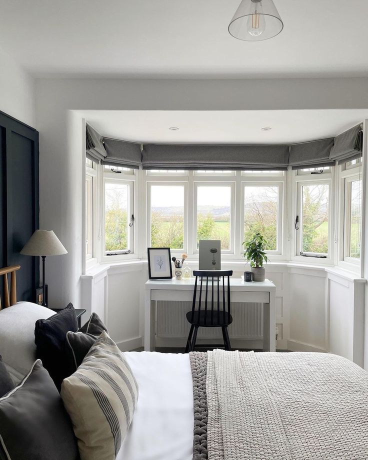 a bedroom with a bed, desk and chair in it's corner window sill