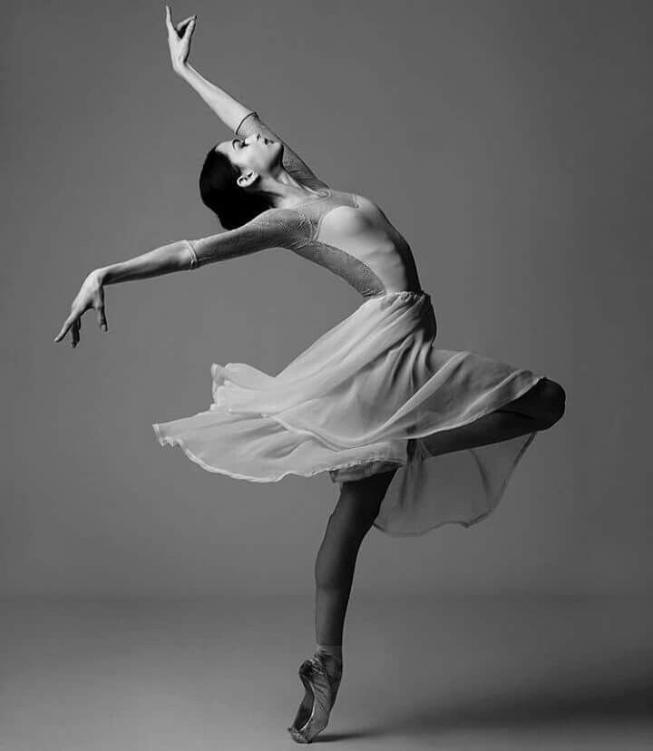 a ballerina in a white dress is doing an acrobatic dance pose