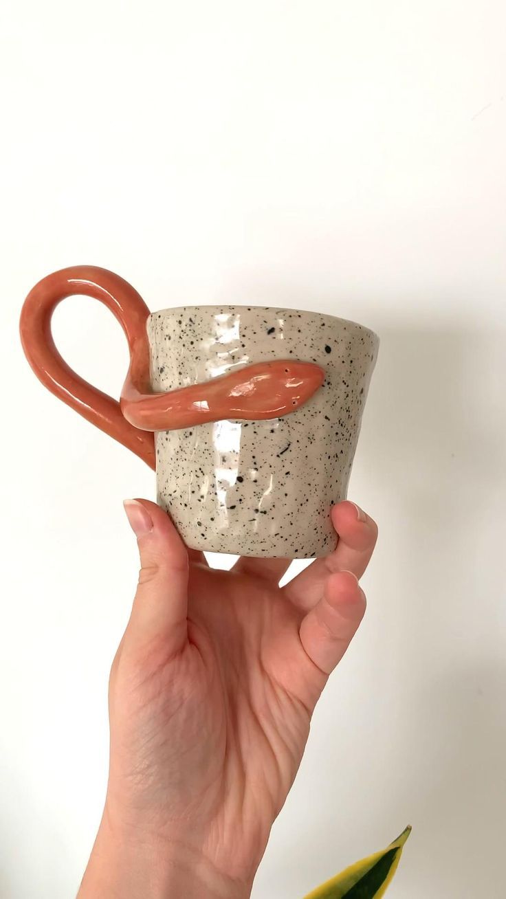 a hand holding a coffee mug with a pretzel handle