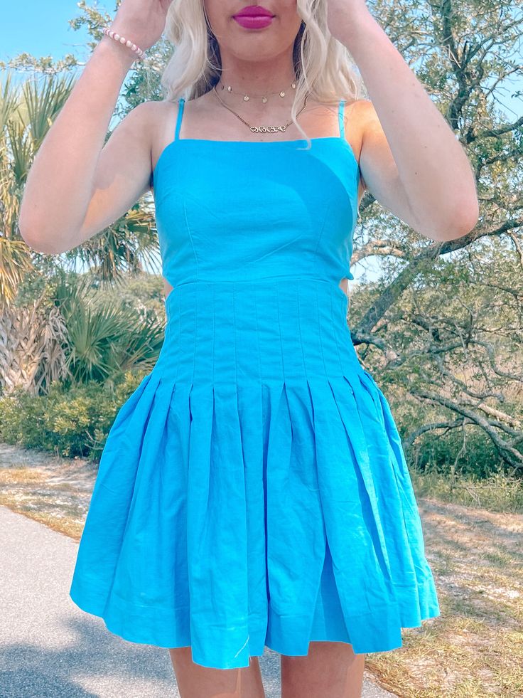 Our Twisted Teal Dress is an electric blue beauty featuring adjustable straps, side cutouts, a pleated fit, and an open tie back. Model is wearing a size small. Lined. content: 65% cotton, 35% linen Blue Mini Dress With Adjustable Straps For Spring, Blue Dresses With Adjustable Straps And Strappy Back, Blue Dress With Adjustable Straps And Strappy Back, Pleated Sundress For Day Out, Blue Sundress With Adjustable Straps For Spring, Chic Blue Sundress With Tie Straps, Fitted Pleated Summer Sundress, Fitted Summer Sundress With Pleats, Linen Dresses With Smocked Back And Spaghetti Straps