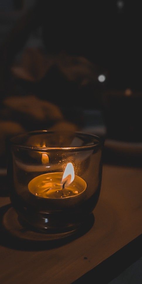 a lit candle in a glass bowl on a table