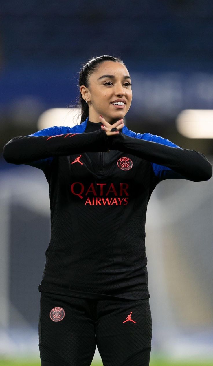 a woman standing on top of a soccer field holding her hands over her face and looking at the camera