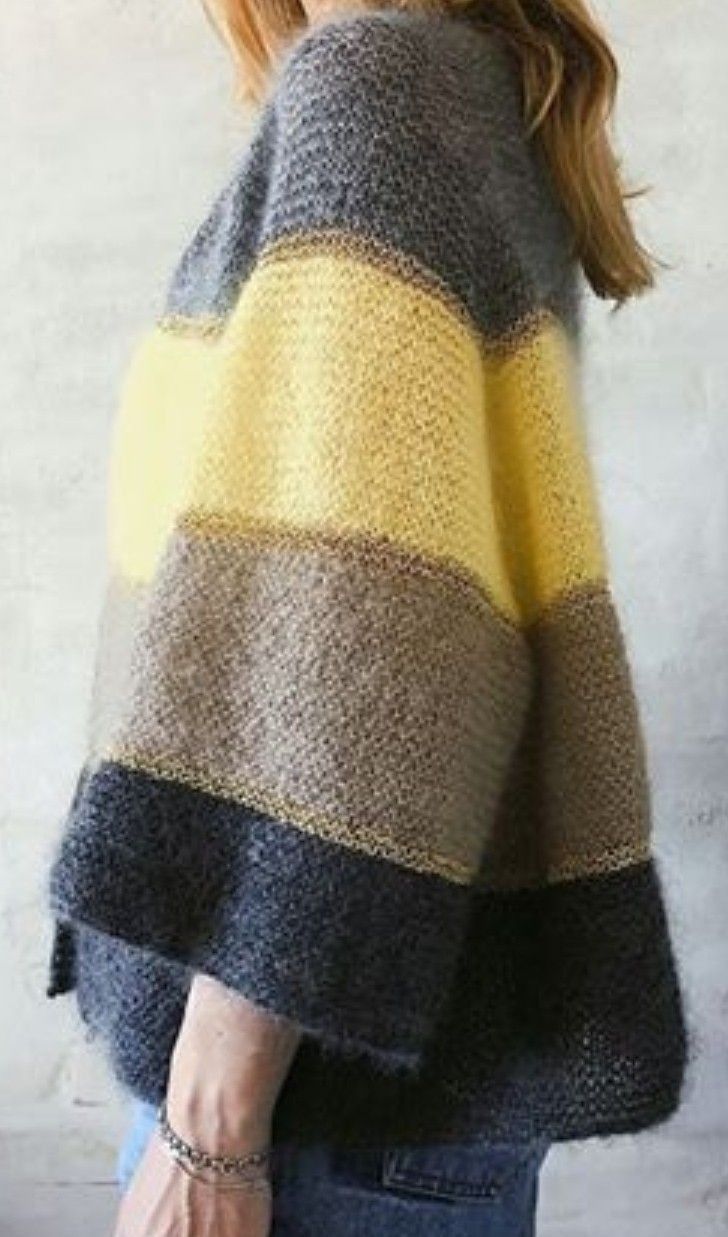 a woman is wearing a sweater with yellow and grey stripes on the back, she has her hands in her pockets