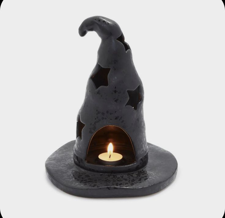 a small black witch hat with a lit candle in it's center and stars on the side