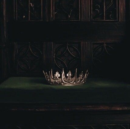 a crown sitting on top of a green cloth covered bench in front of a wooden paneled wall