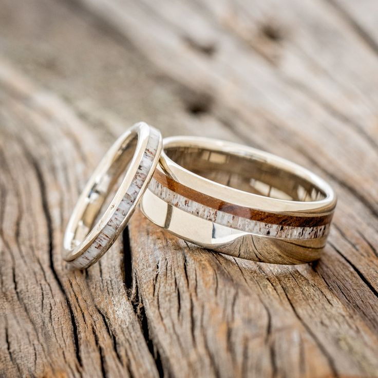 two wedding rings sitting on top of a wooden table