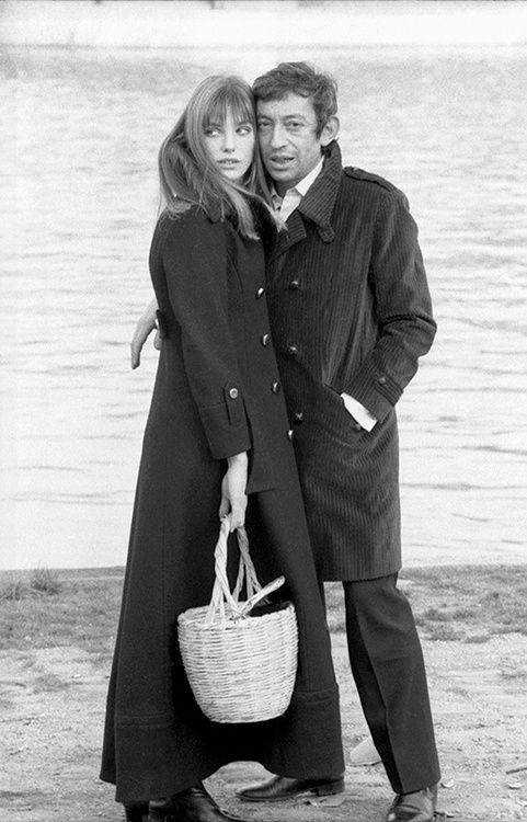 a man and woman standing next to each other in front of a body of water