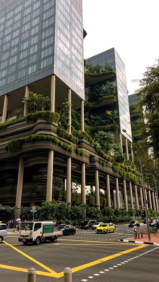 a very tall building with many plants growing on it's sides in the city