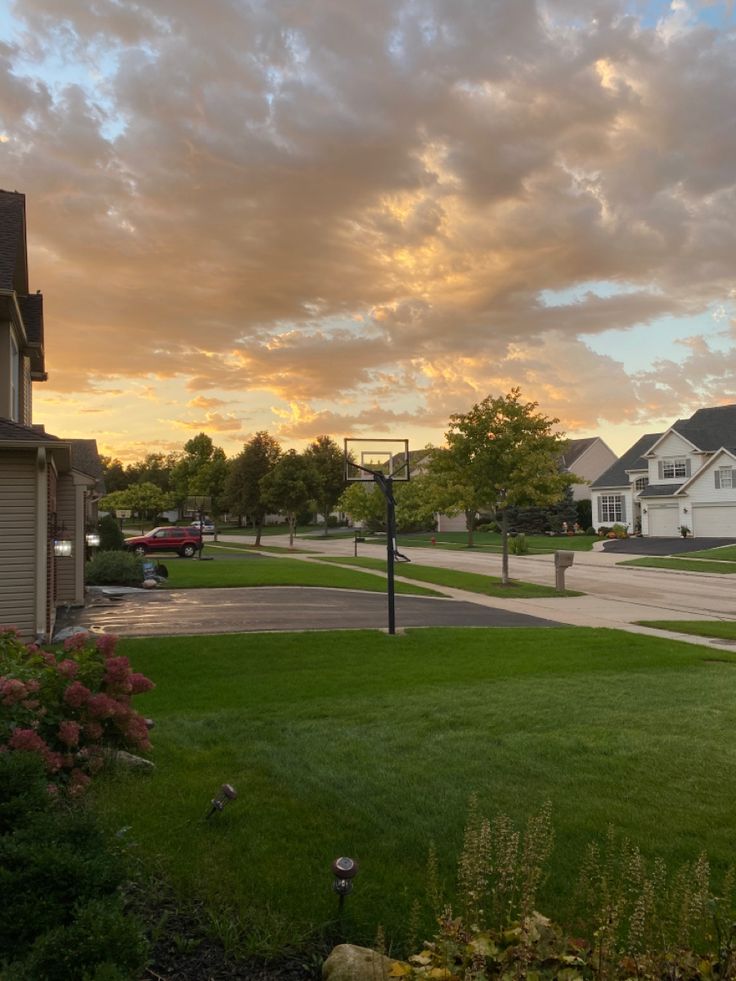 the sun is setting over some houses and lawns