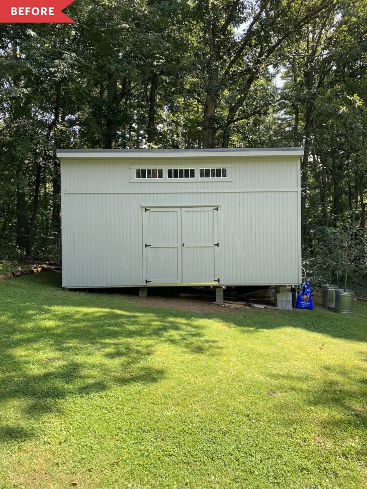 a white shed sitting on top of a lush green field