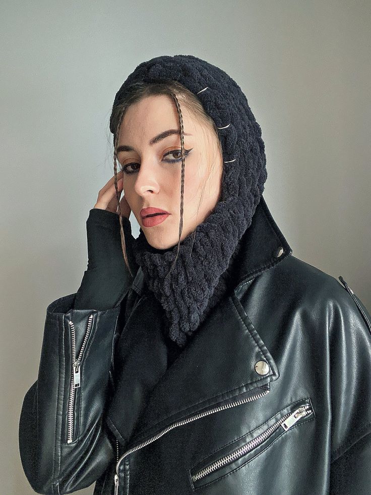 a woman wearing a black leather jacket and a knitted cowgirl hat with metal spikes on her head