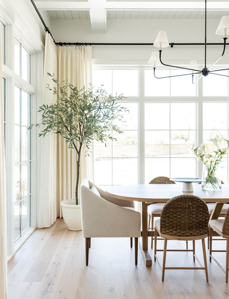 the dining room table is surrounded by beige chairs and white walls, along with large windows