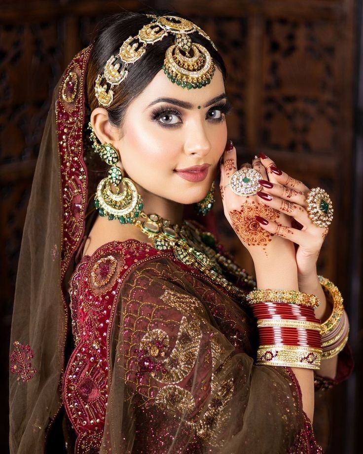 a woman in a red and gold outfit with jewelry on her head, posing for the camera