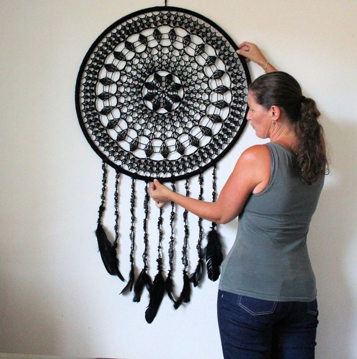 a woman is working on a black and white dream catcher wall hanging in her living room