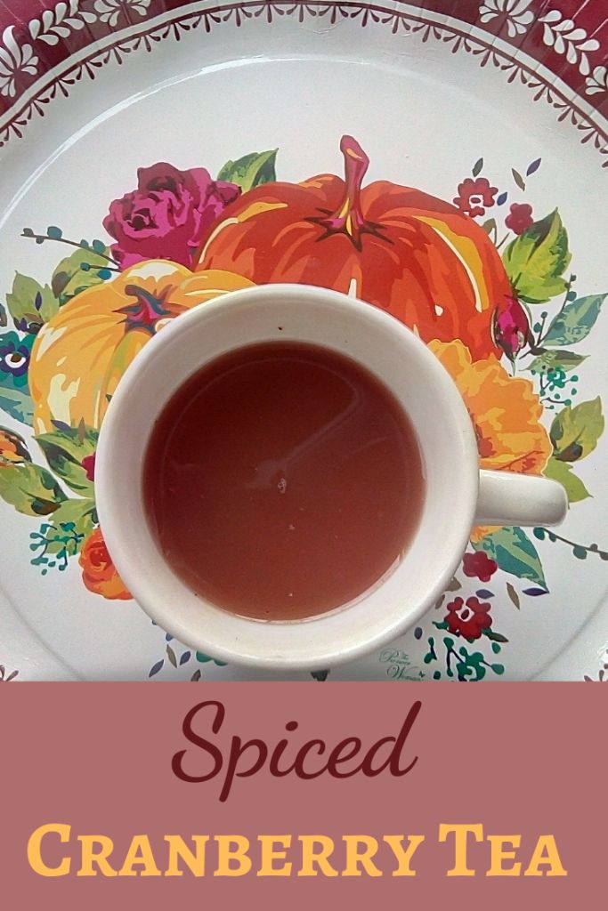 a cup of tea on a plate with the words spiced cranberry tea