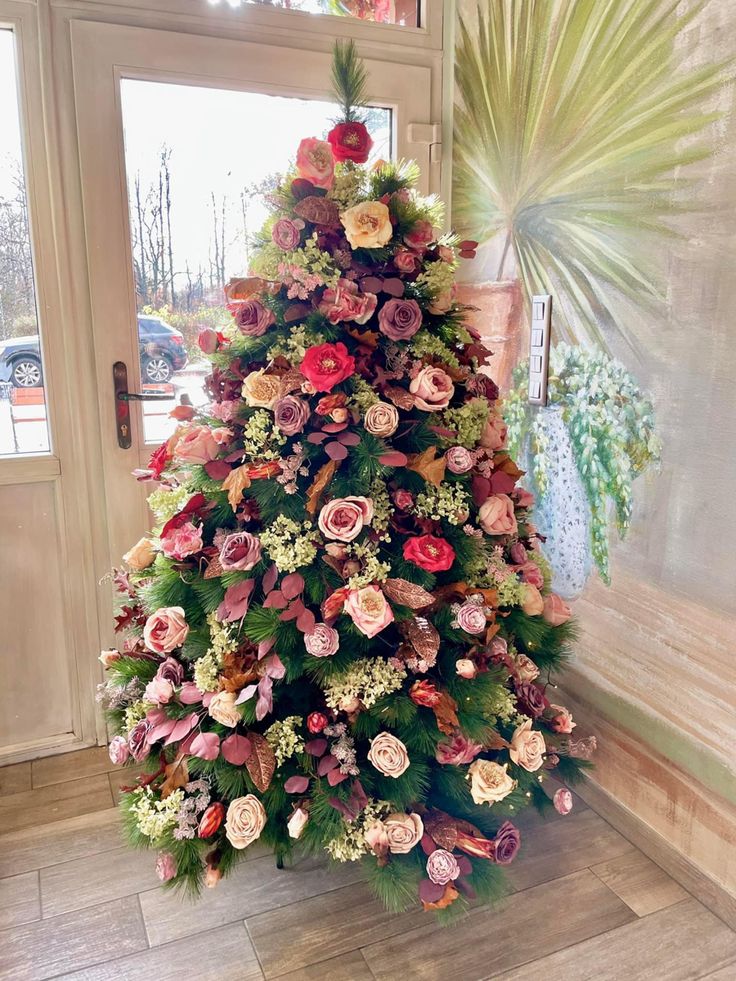 a christmas tree is decorated with flowers and greenery