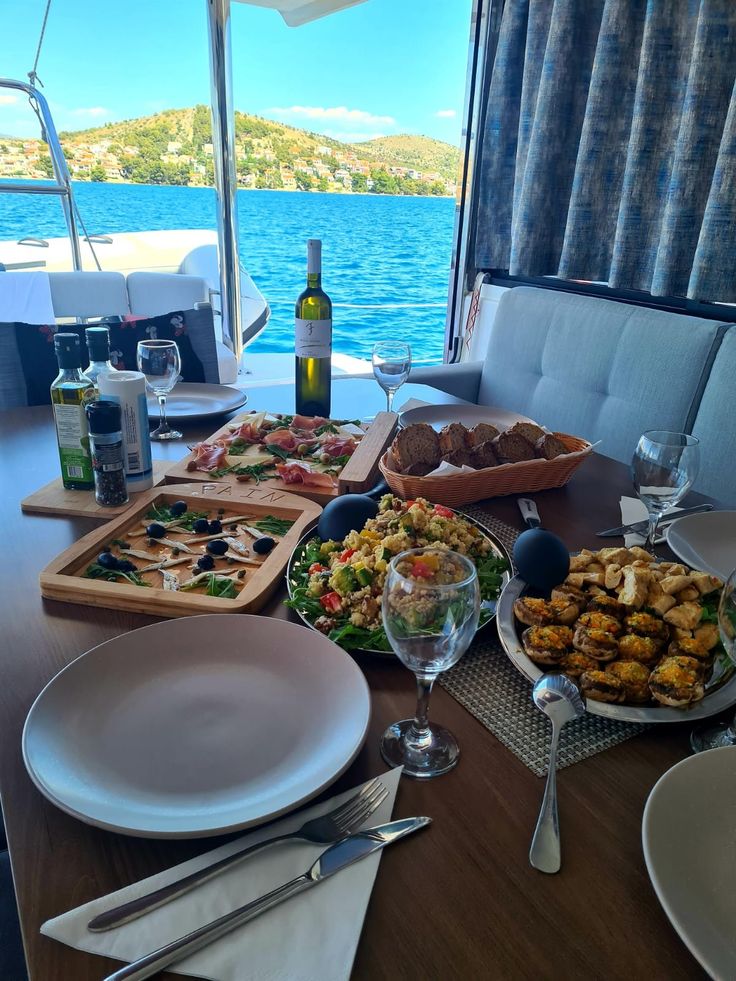 the table is set with food and wine on it, along with other dishes that include appetizers