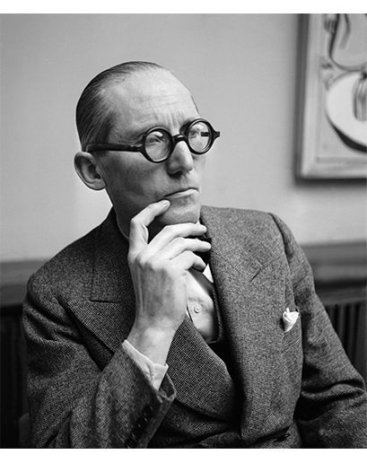 a black and white photo of a man with glasses looking off to the side while holding his hand on his chin