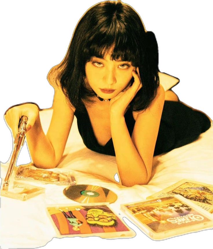 a woman laying on top of a bed next to cd's