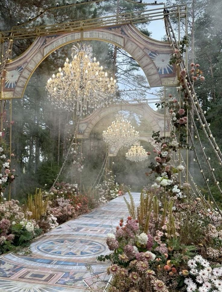 a garden with flowers and chandeliers hanging from the ceiling, surrounded by greenery