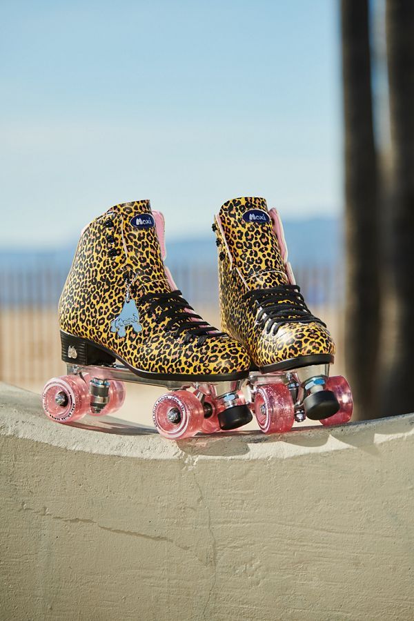 a pair of leopard print shoes sitting on top of a wall next to a skateboard