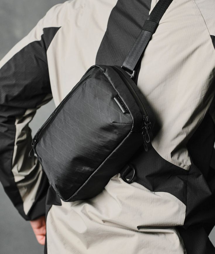 a man wearing a black bag with his back to the camera and holding it in his hand