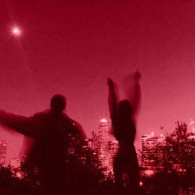 two people standing in front of a red sky with their arms up and hands raised