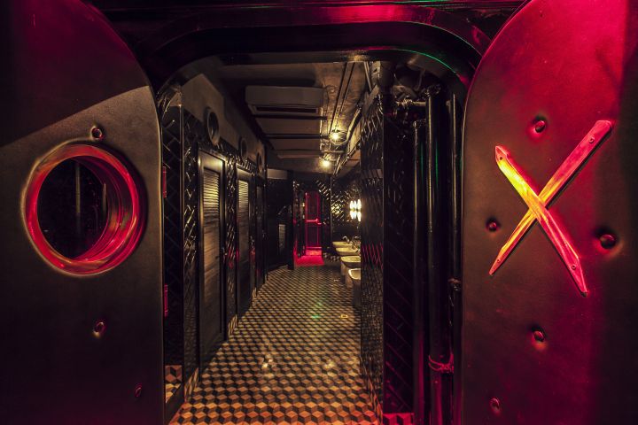 a hallway with black and white checkered flooring and red lights on the walls