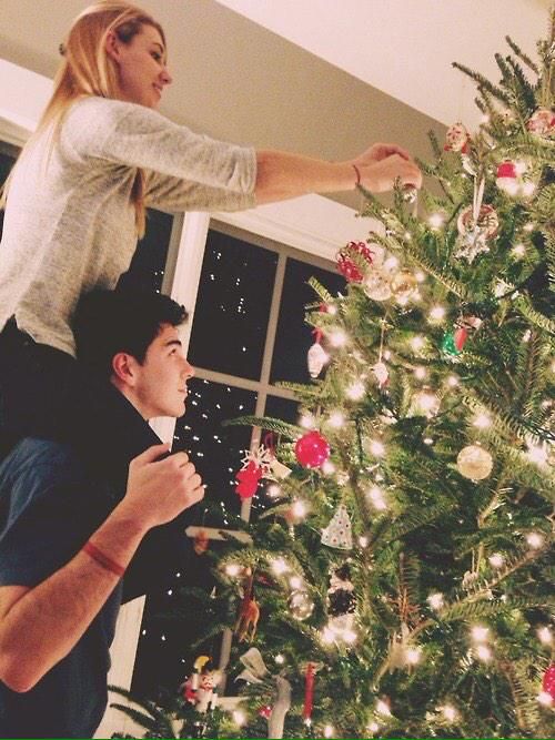 a man and woman decorating a christmas tree