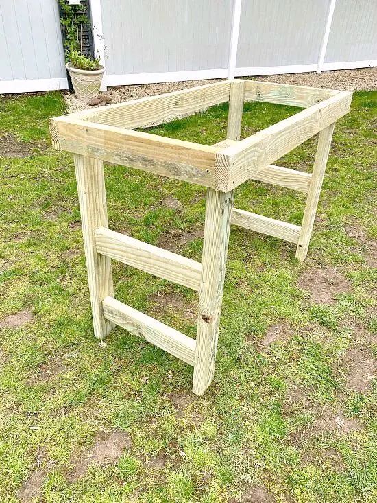 a wooden planter sitting on top of a lush green field