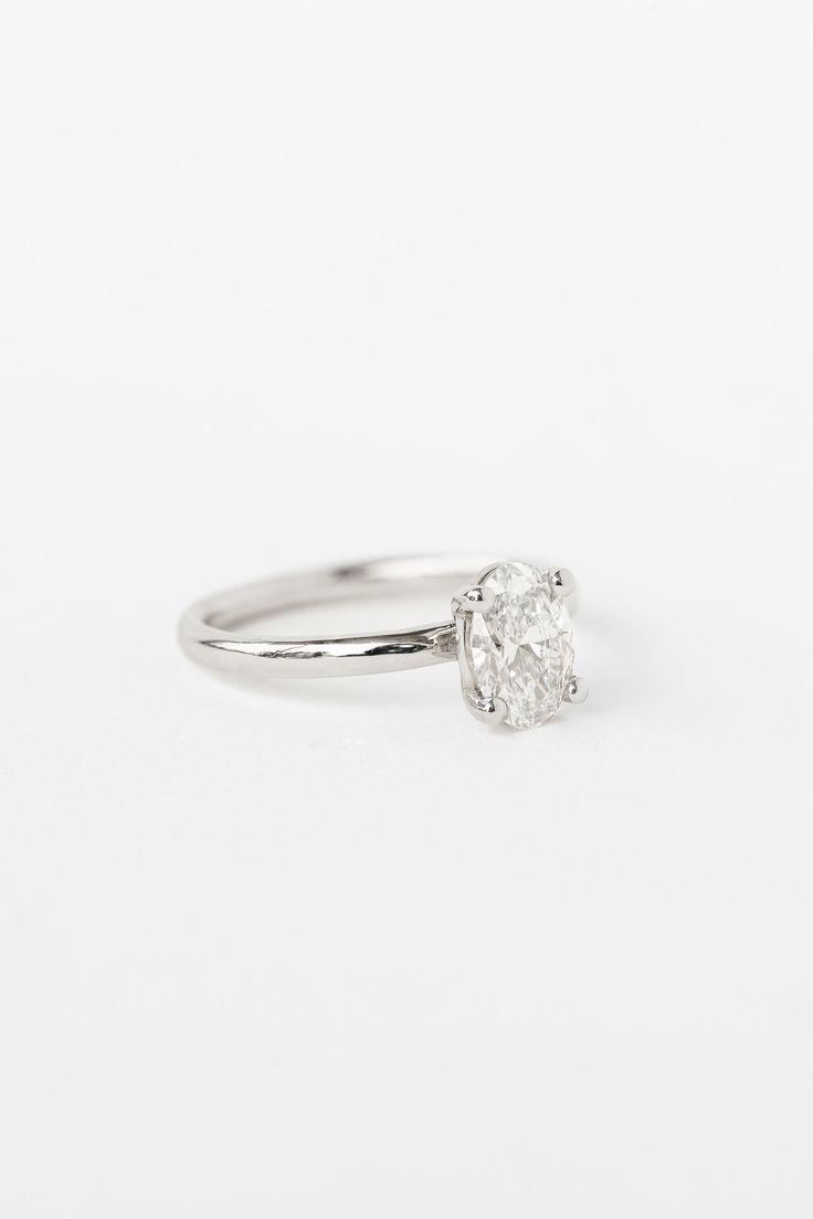 a white gold engagement ring with a single diamond in the center, on a white background