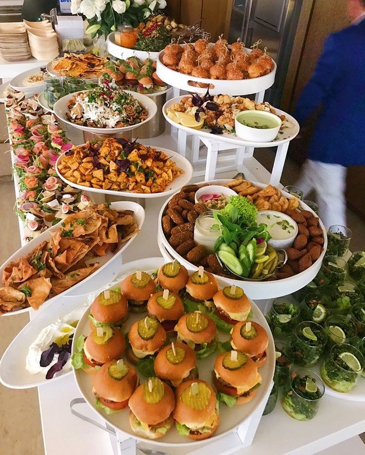 a buffet table filled with lots of different types of food on white plates and serving platters