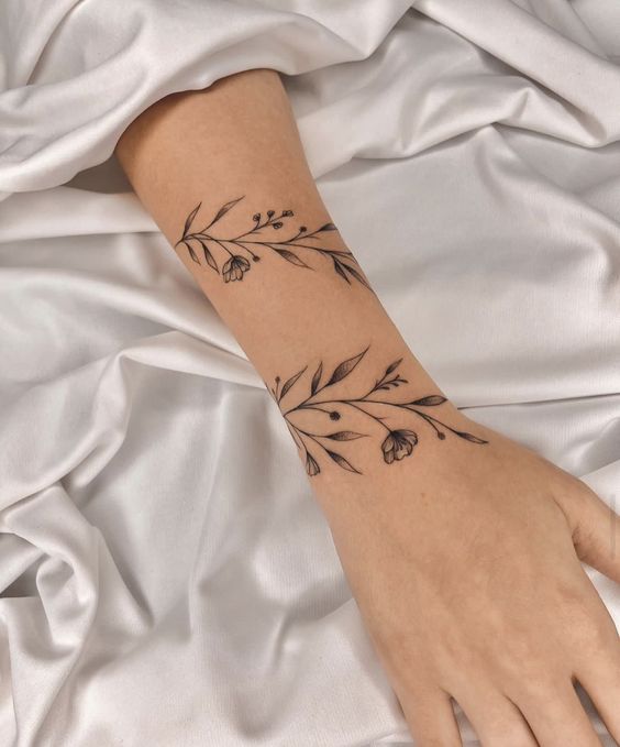 a woman's hand with a black flower tattoo on her left arm and wrist