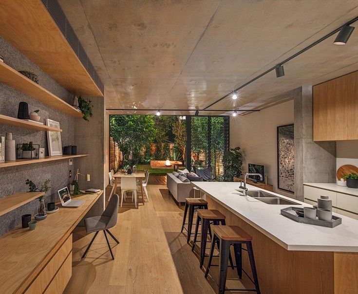 an open concept kitchen and dining area with wood flooring, built in shelving units and bar stools