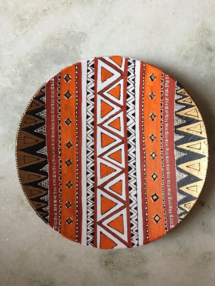 an orange and white plate with designs on the top is sitting on a concrete surface