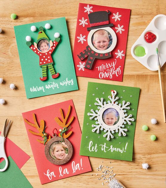 four christmas cards on a table with scissors and other holiday items in the foreground