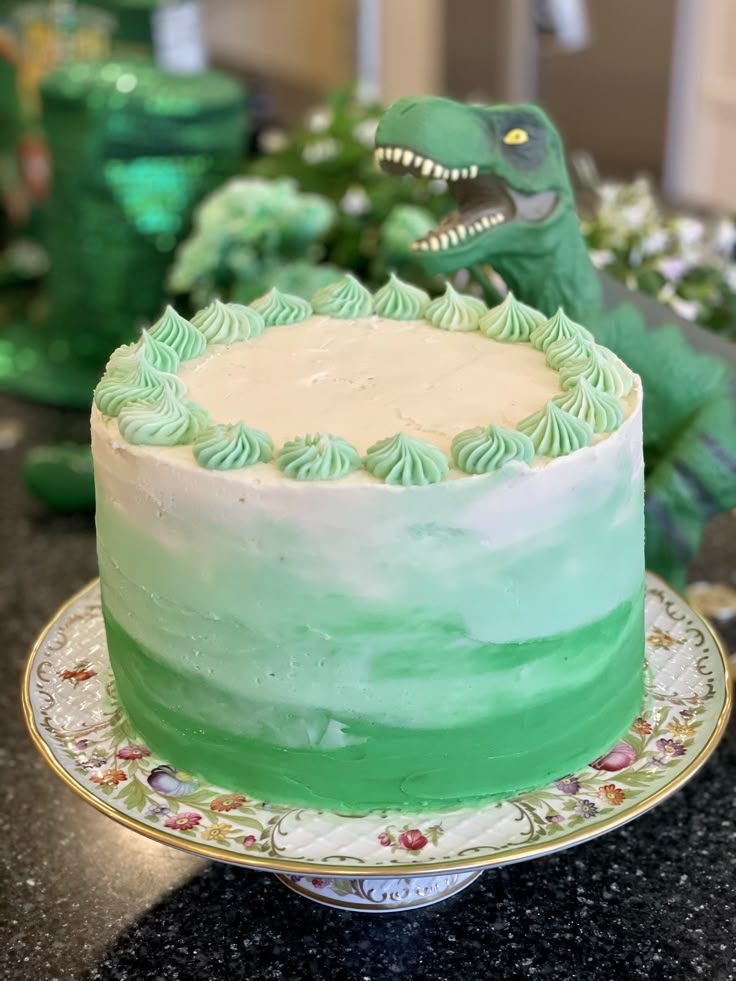 a dinosaur cake with green frosting on a plate