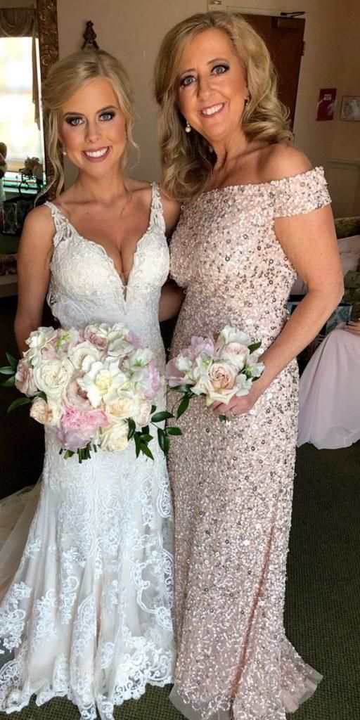 two women standing next to each other in formal dresses and holding bouquets on the floor