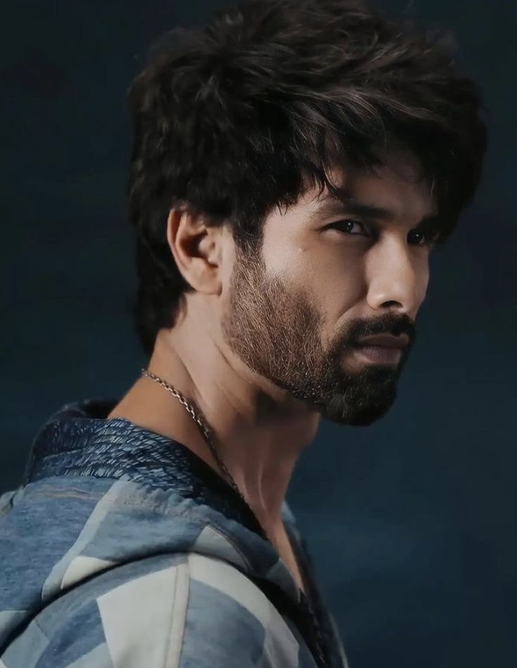 a man with dark hair and beard wearing a blue shirt