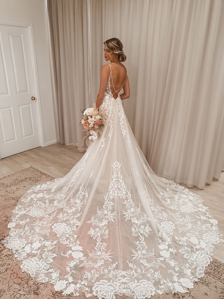 a woman standing in front of a white door wearing a wedding dress and holding a bouquet