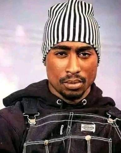 a man wearing a black and white hat with stripes on it's head, standing in front of a gray background