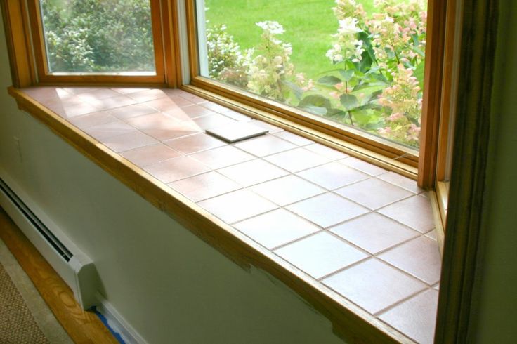 an open window in a room with tile flooring and green grass outside the window