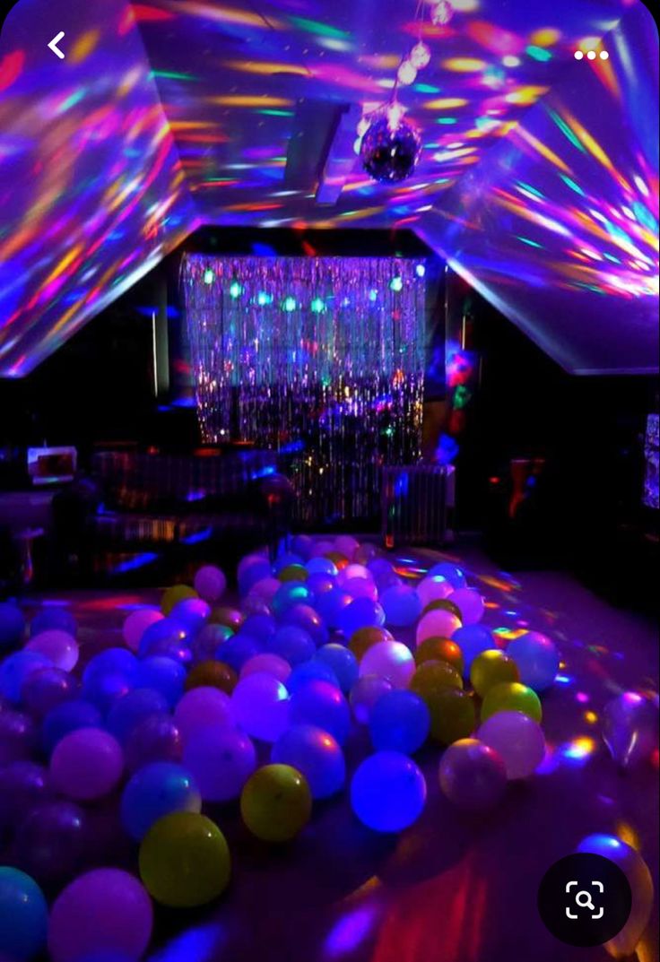 a room filled with lots of balloons and disco lights on the ceiling, all lit up