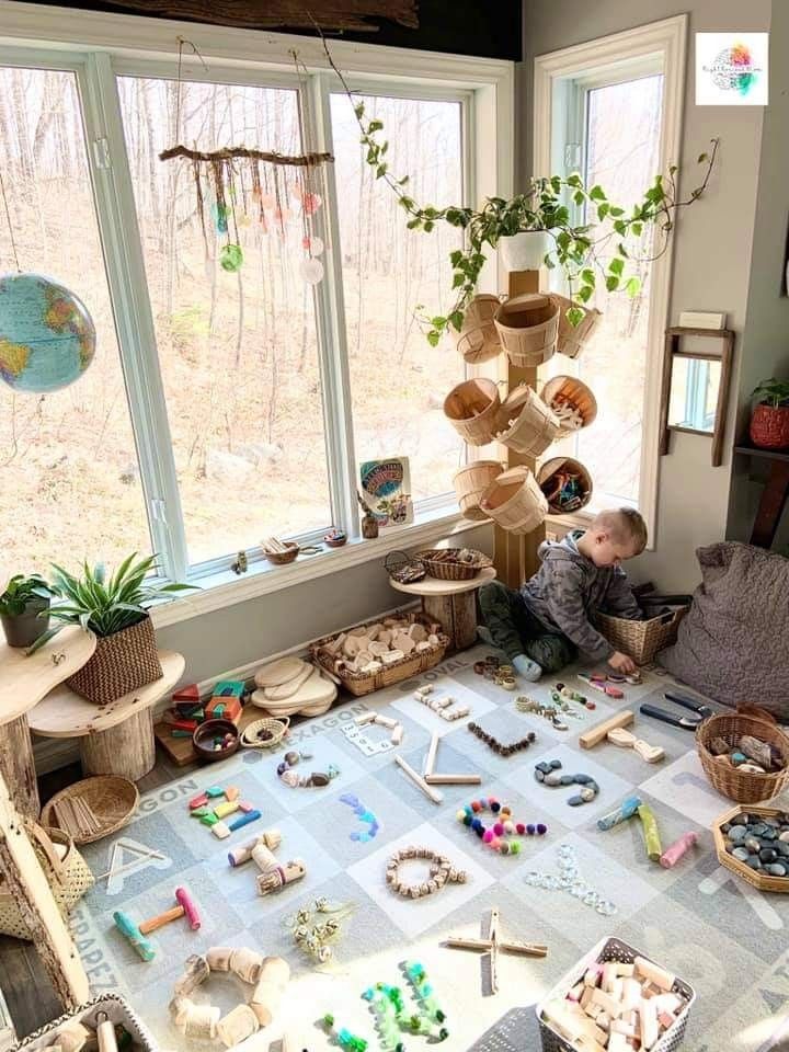 a young boy sitting on the floor in front of a window with lots of toys