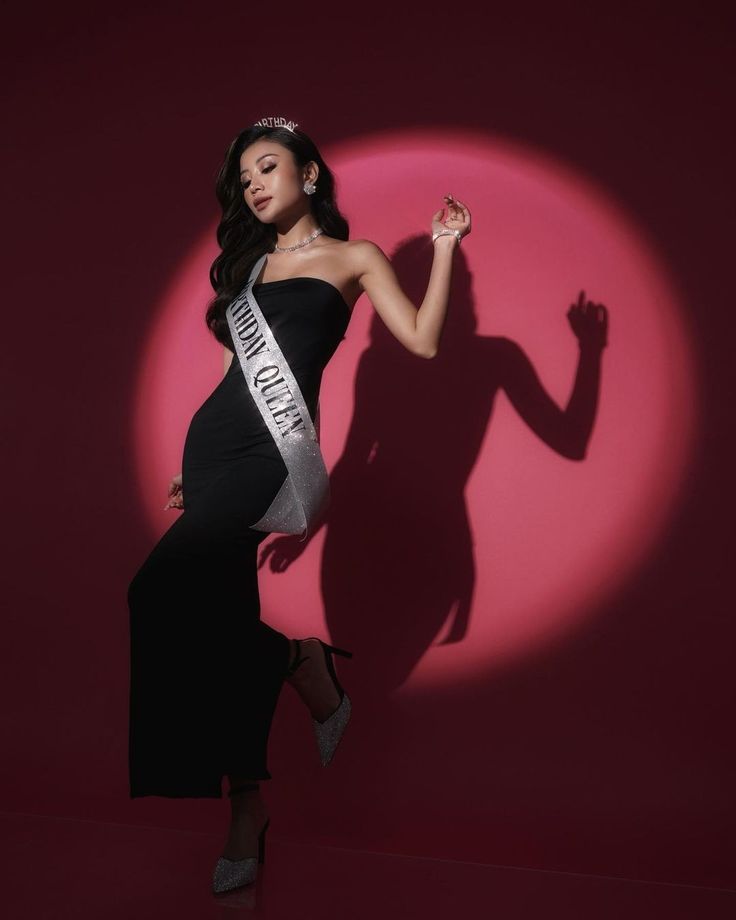 a woman in a black and white dress posing for a photo with her shadow on the wall