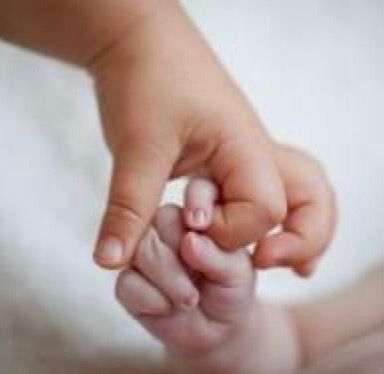 a close up of a baby's hand holding the finger of an adult who is laying down