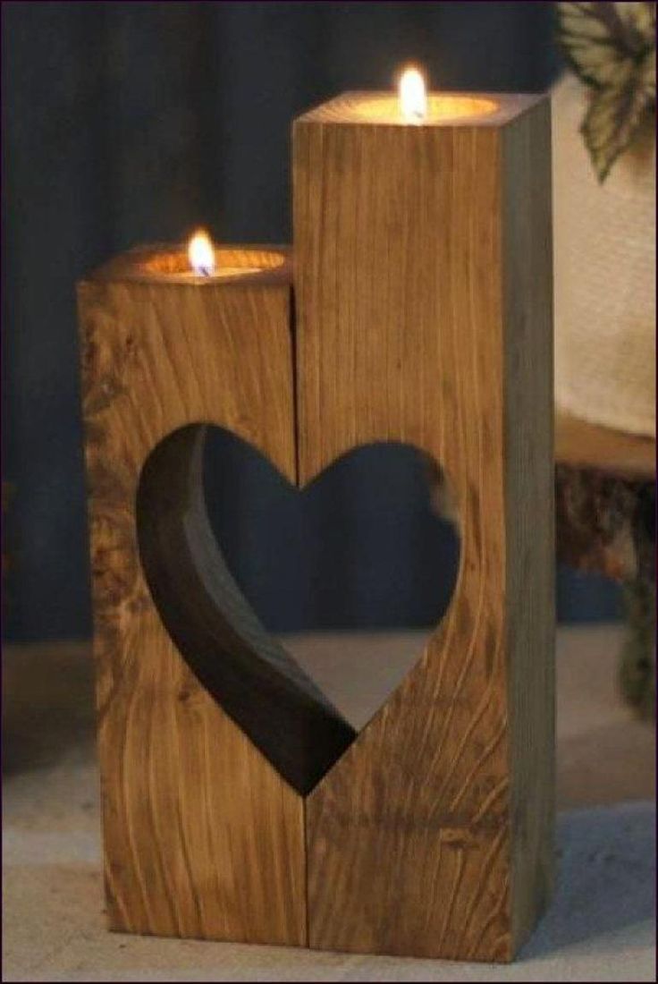 a wooden block with a heart cut out of it and two candles in the middle