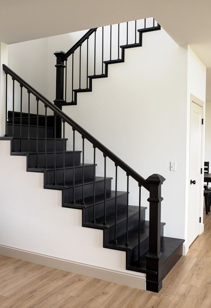 there is a black stair case on the wall next to the wooden floor in this living room