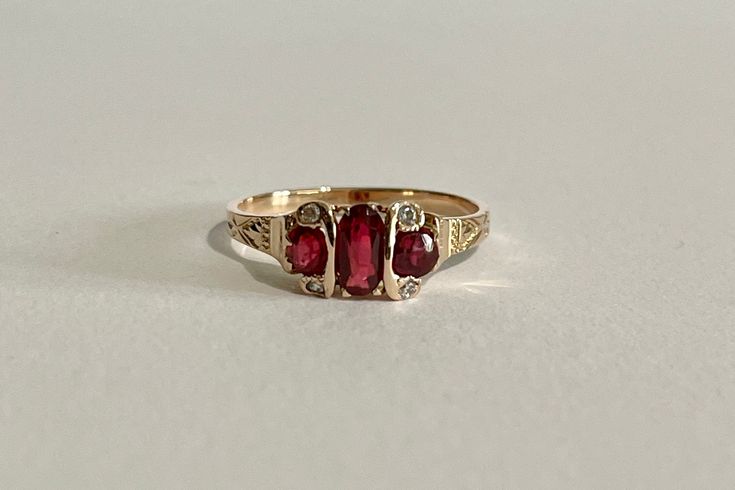 This is a gorgeous Edwardian Era 14k Yellow Gold Garnet Ring with a three genuine garnets and four white sapphire gemstone setting, the middle garnet is oval faceted cut the two side ones are faceted round cut, with four rose cut white sapphires one on each corner. A stunning piece of fine early 1900s era jewelry, featuring January's birthstone! ERA - Circa 1900s / Edwardian METAL / MATERIAL - 14k yellow gold, 3 genuine garnets (approx. 0.77 CTW), 4 white sapphires (approx. 0.02 CTW) MARKINGS / Edwardian Garnet Ring, Gold And Garnet Jewelry, Three Stone Ruby Ring In 14k Yellow Gold, Antique Three Stone 14k Gold Jewelry, Victorian 14k Gold Three-stone Ring, Victorian Three Stone 14k Gold Ring, Antique Three-stone Ruby Wedding Ring, Heirloom Ruby Ring With Vvs Clarity In 14k Gold, Heirloom Three Stone Red Rings