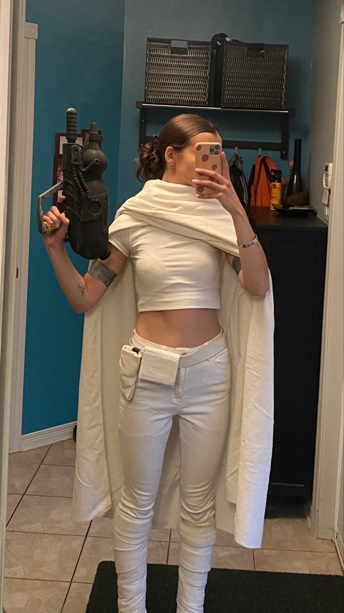 a woman is taking a selfie in the mirror wearing white pants and a crop top